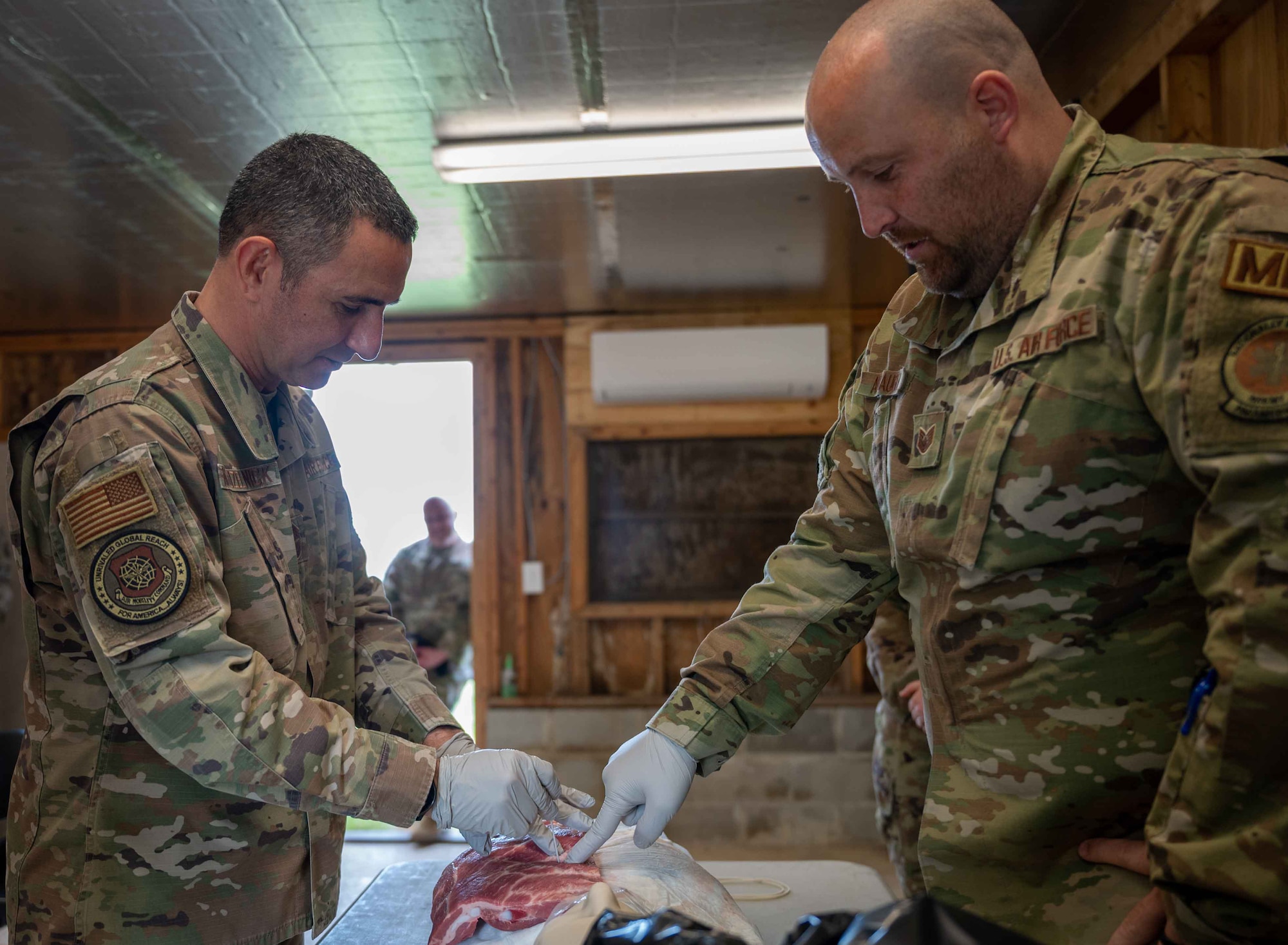 Chief Master Sgt. Brian Kruzelnick, left, Air Mobility Command command chief, practices needle decompression techniques with Tech. Sgt. Brock Ashbaugh, 436th Medical Group tactical combat casualty care instructor, at Dover Air Force Base, Delaware, May 5, 2022. During the visit, Kruzelnick and Gen. Mike Minihan, AMC commander, highlighted top performing Airmen and visited base facilities such as the C-5 isochronal dock, the air traffic control tower and the Tactics and Leadership Nexus complex. (U.S. Air Force photo by Senior Airman Faith Schaefer)