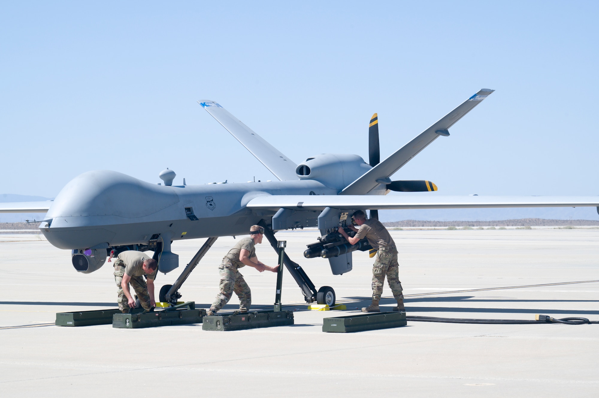 Airmen from the 163rd Attack Wing, out of March Air Reserve Base, load inert training weapons to an MQ-9 Reaper at Edwards Air Force Base, California, May 4. The aircraft conducted an Agile Combat Employment (ACE) to a Forward Operating Site (FOS), flying from March Air Reserve Base to Edwards Air Force Base. (Air Force photo by Giancarlo Casem)