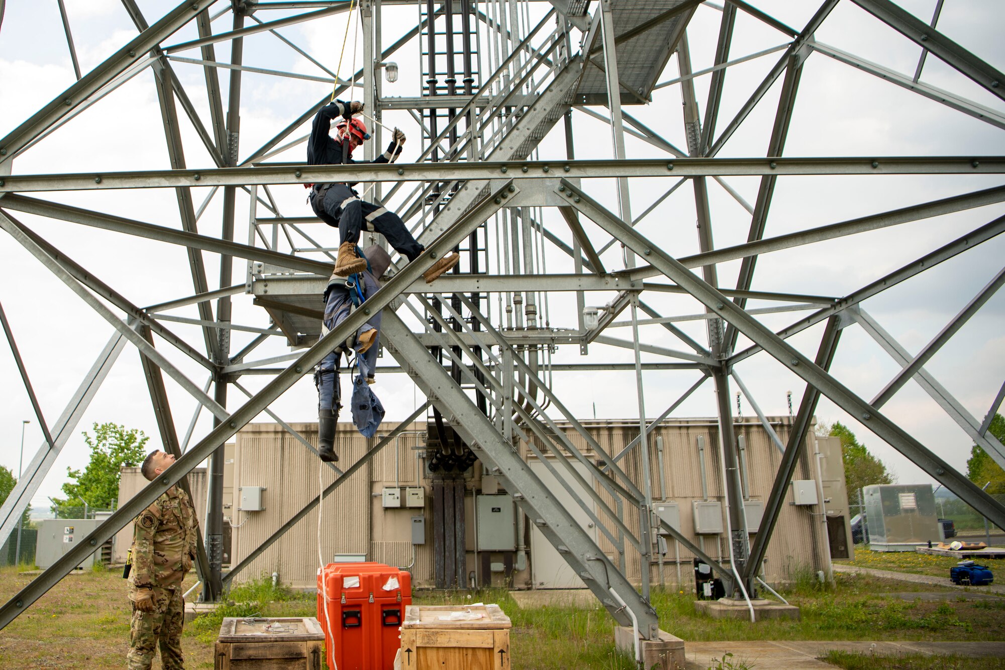 Airman 1st Class Issac Painter, 52nd Civil Engineer Squadron firefighter, rappels down a radio tower with a rescue dummy during a Fall Rescue demonstration, May 4, 2022, on Spangdahlem Air Base, Germany. The demonstration was held to show how firefighters rescue someone who has fallen over the side of a radar tower and to stress the importance of using fall protection equipment correctly. (U.S. Air Force photo by Airman 1st Class Jessica Sanchez-Chen)