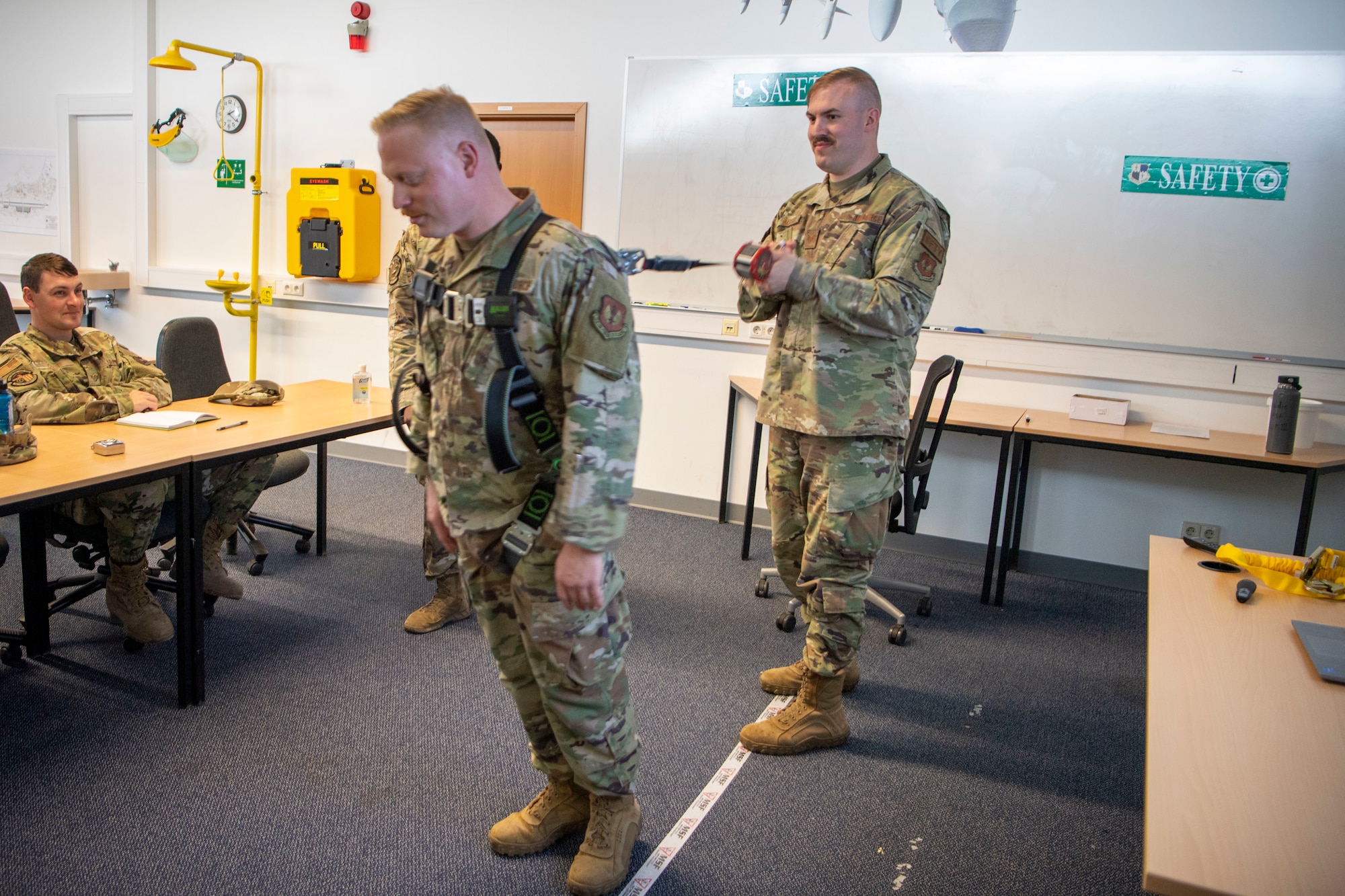 Staff Sgt. Jacob Bass, right, 52nd Fighter Wing Safety occupational safety technician, and Tech Sgt. Josiah Sorrels, 52nd Civil Engineer Squadron structural technician, demonstrate using a shock absorbing lanyard, May 3, 2022, on Spangdahlem Air Base, Germany. The 52nd FW Safety office hosted a Fall Protection Training Course to teach the importance and proper use of fall protection equipment. (U.S. Air Force photo by Airman 1st Class Jessica Sanchez-Chen)