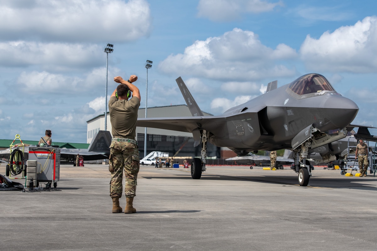 A crew chief signals to an F-35A Lightning II pilot from the flightline