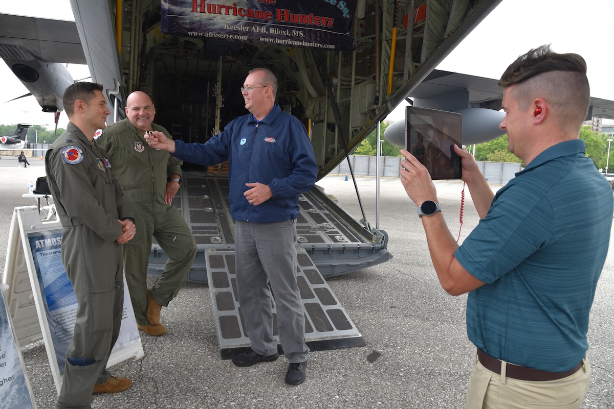 Two NOAA members video and interview two Air Force Reserve Hurricane Hunters behind a WC-130J Super Hercules.