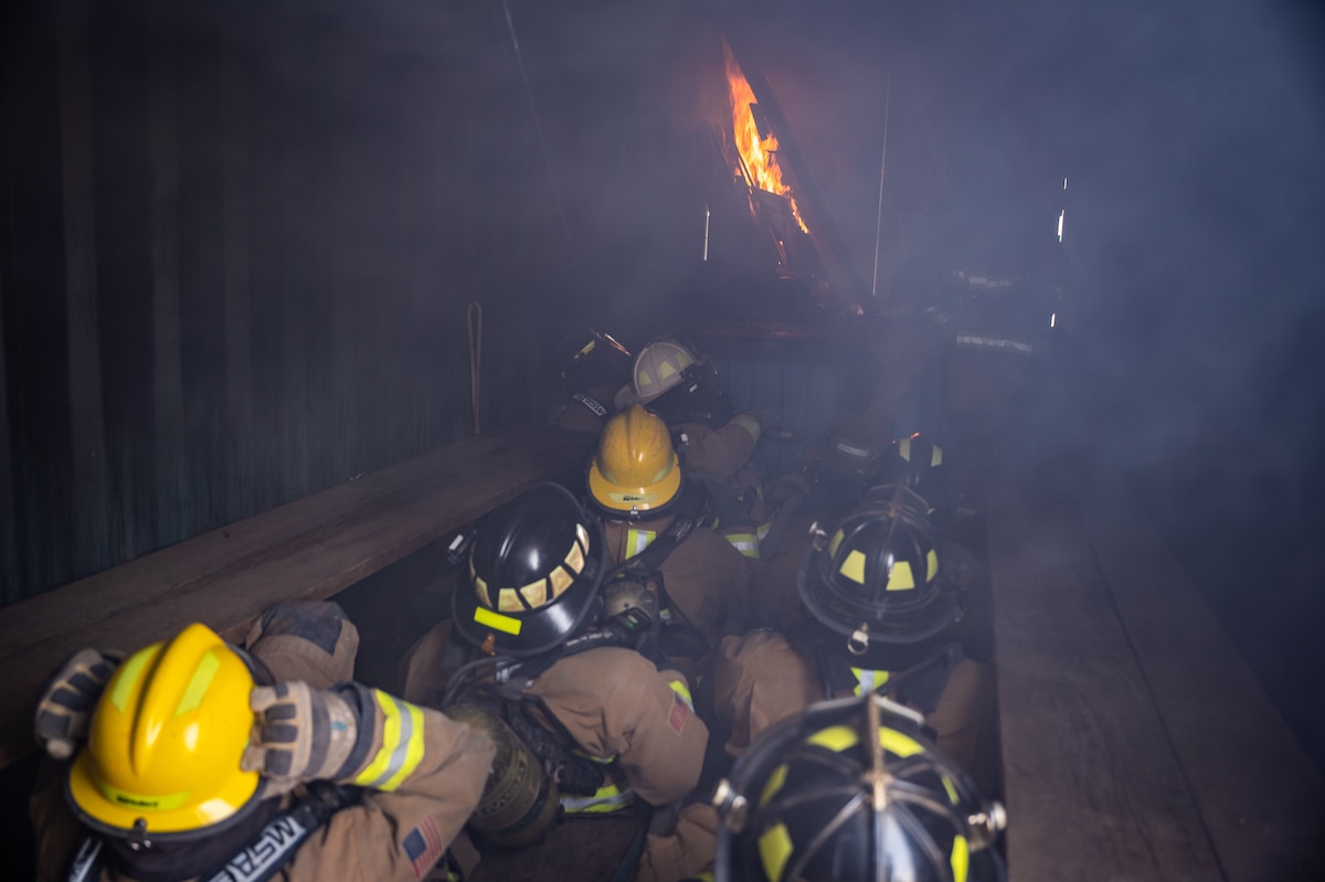 332d Expeditionary Civil Engineer Squadron firefighters sit inside the flashover trainer, as a fire begins to grow during live-fire flashover training at an undisclosed location in Southwest Asia, April 30, 2022. (U.S. Air Force photo by Master Sgt. Christopher Parr)