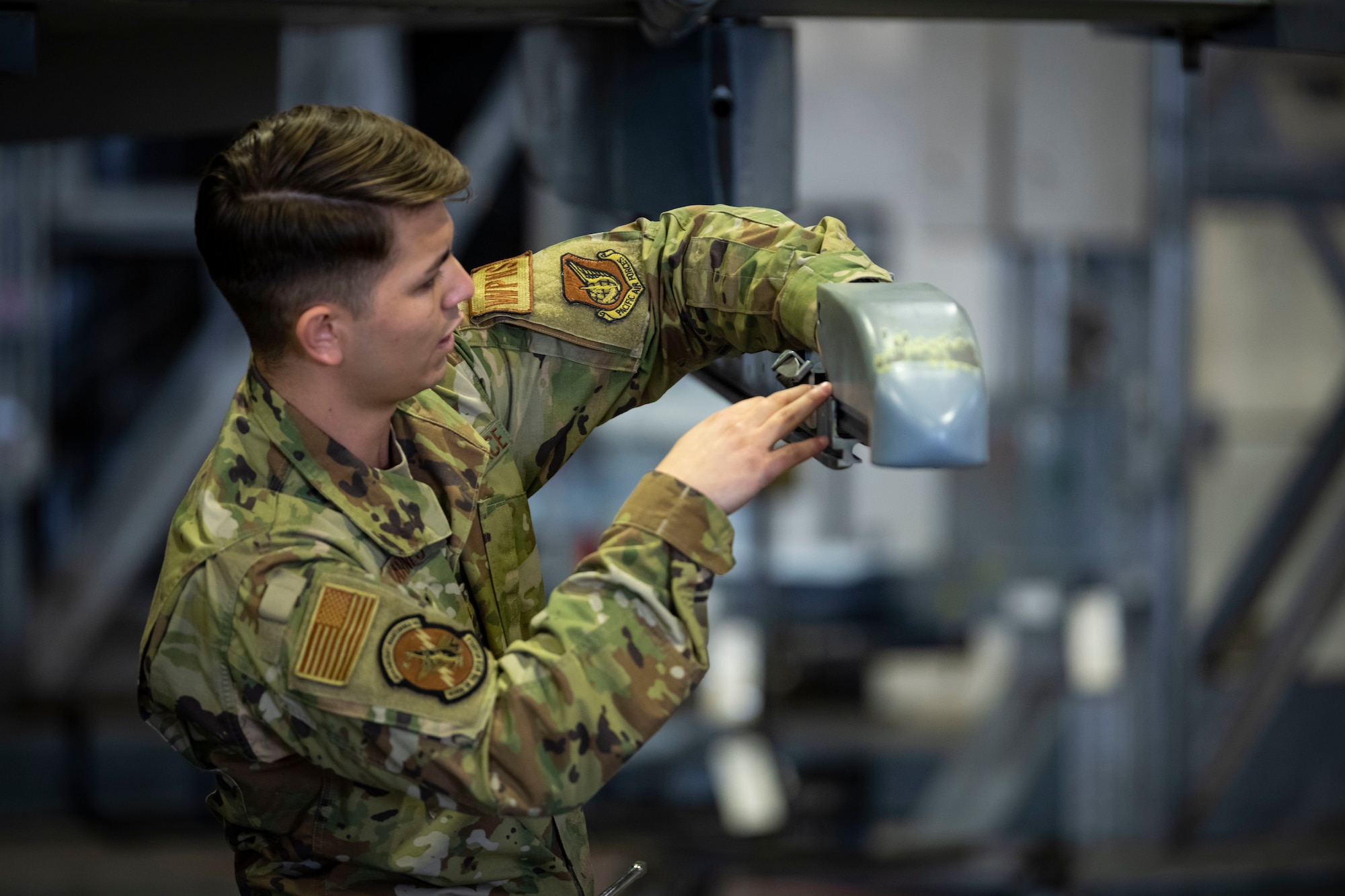 Military member in uniform prepares to load munitions onto an F-16.