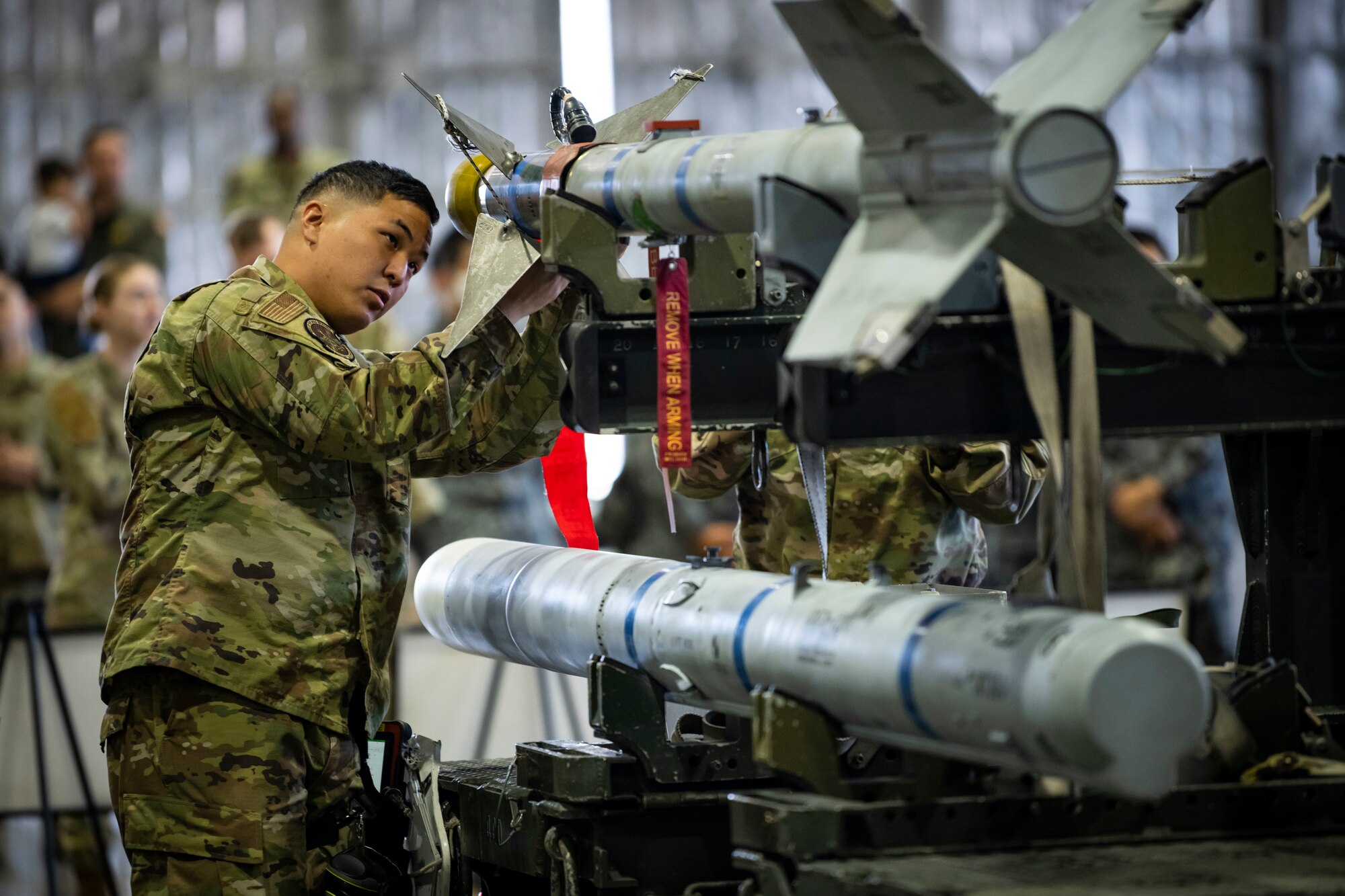 Military members in uniform load munitions onto an F-16.