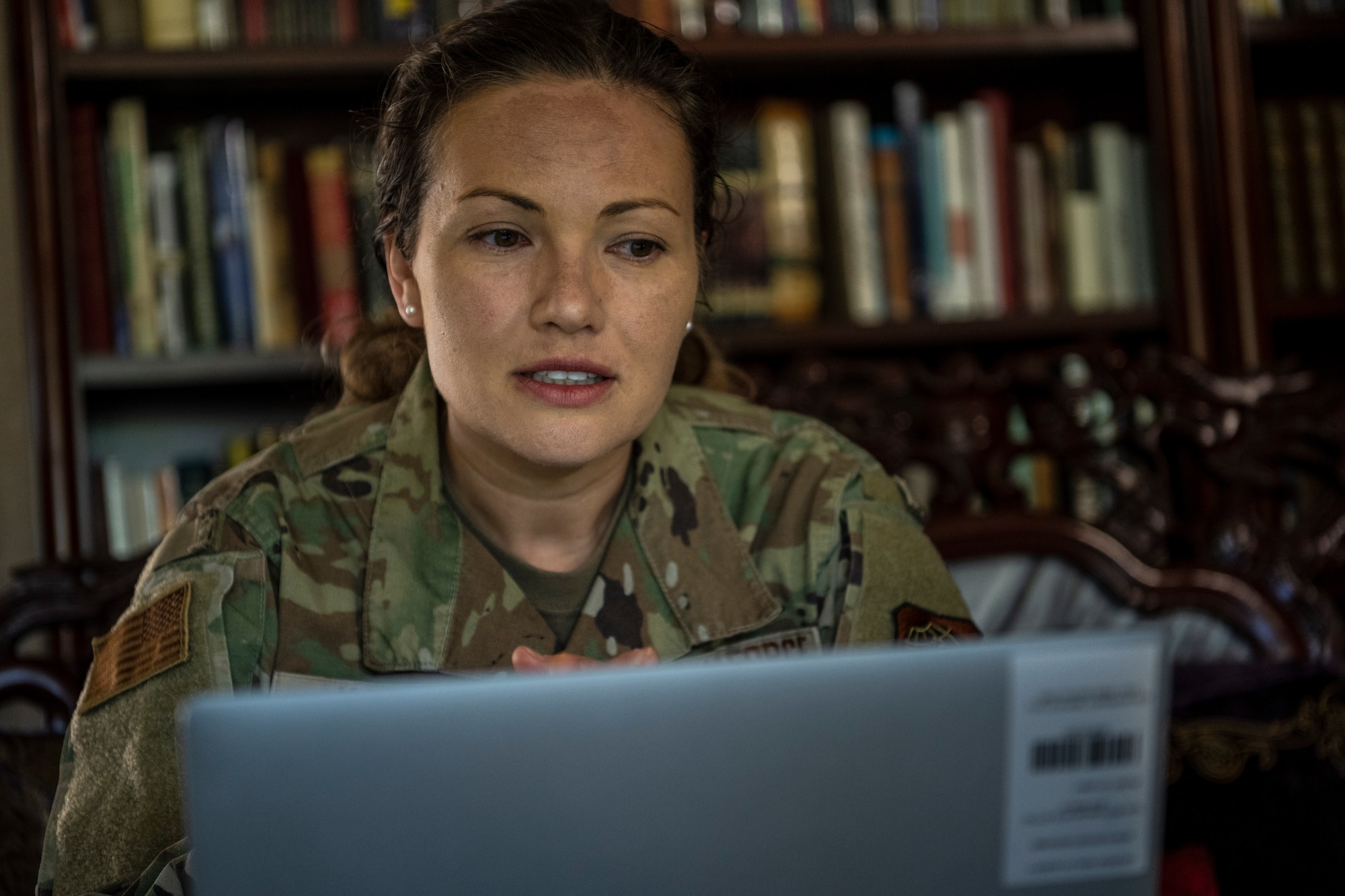 A woman sits in front of a laptop.