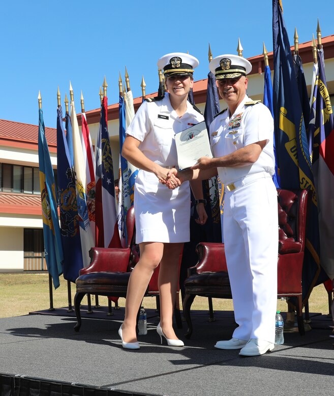 Ensign Julianna Pereira, a graduate of the U.S. Naval Civil Engineer Corps Officers (CECOS) Basic Class 272 is congratulated by Rear Admiral John W. Korka, commander of Naval Facilities Engineering Systems Command (NAVFAC) and 45th Chief of Civil Engineers upon her selection as honorgraduate.