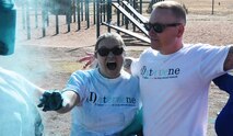 Jess Wilson, (left) 1st Space Brigade’s Sexual Harassment/Assault Response and Prevention (SHARP) Program victim advocate, and Sgt. 1st Class Andrew Ross, 1st Space Brigade Sexual Assault Response Coordinator (SARC), throw colored paint on runners during 1st Space Brigade’s 5K “color run” which raised awareness for the victims of sexual assault and sexual harassment April 29, 2022. (Photo by Sgt. 1st Class Aaron Rognstad/RELEASED).