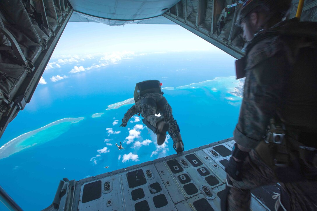 A Marine jumps from an aircraft over open water.