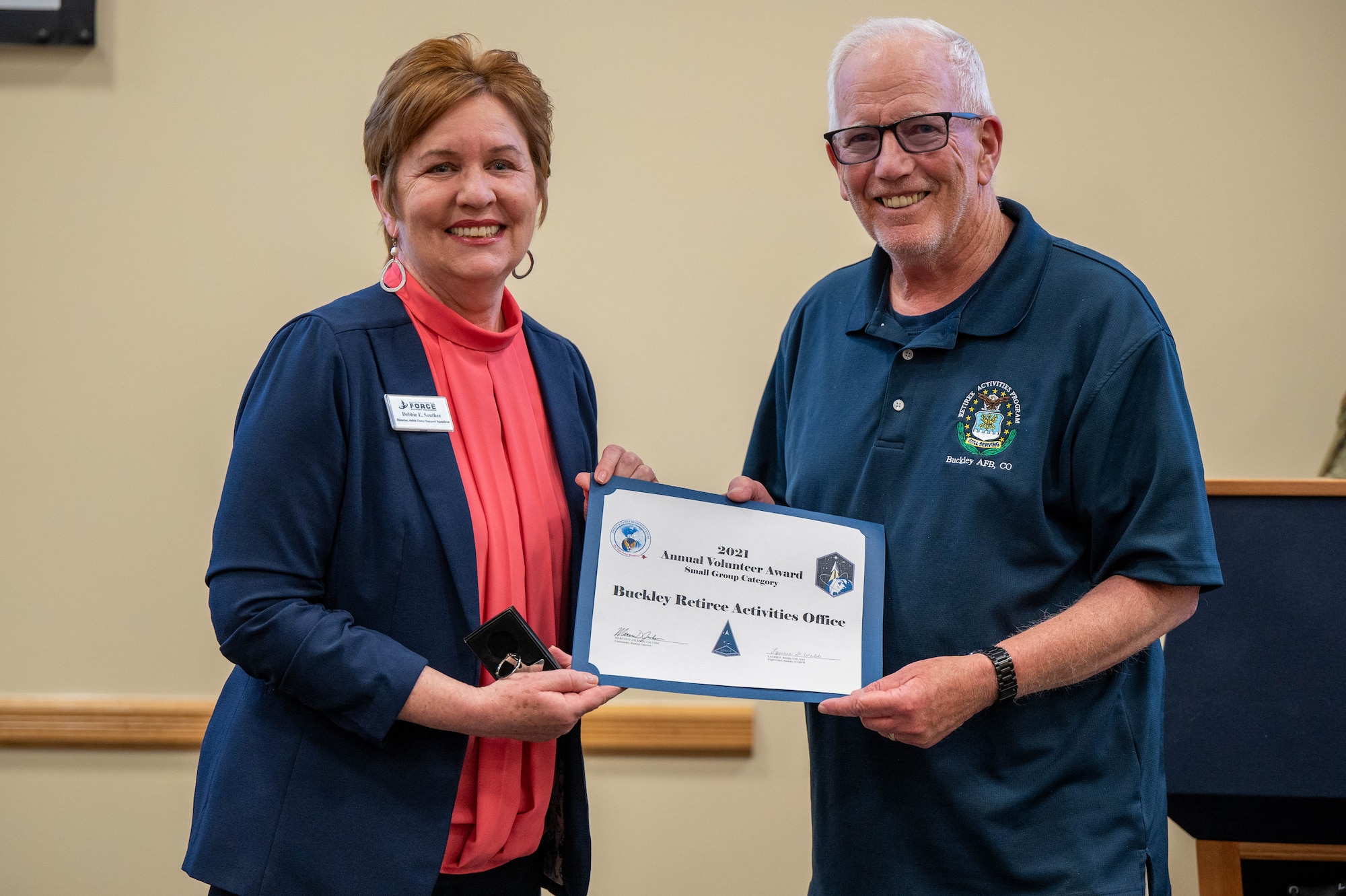 Gary Kelsey, an employee working with the Buckley Retiree Activities office, receives an annual volunteer award for the Retiree Activities office from Mrs. Debbie South, Director of the 460th Force Support Squadron at Buckley Space Force Base, Colo., April 22, 2022.