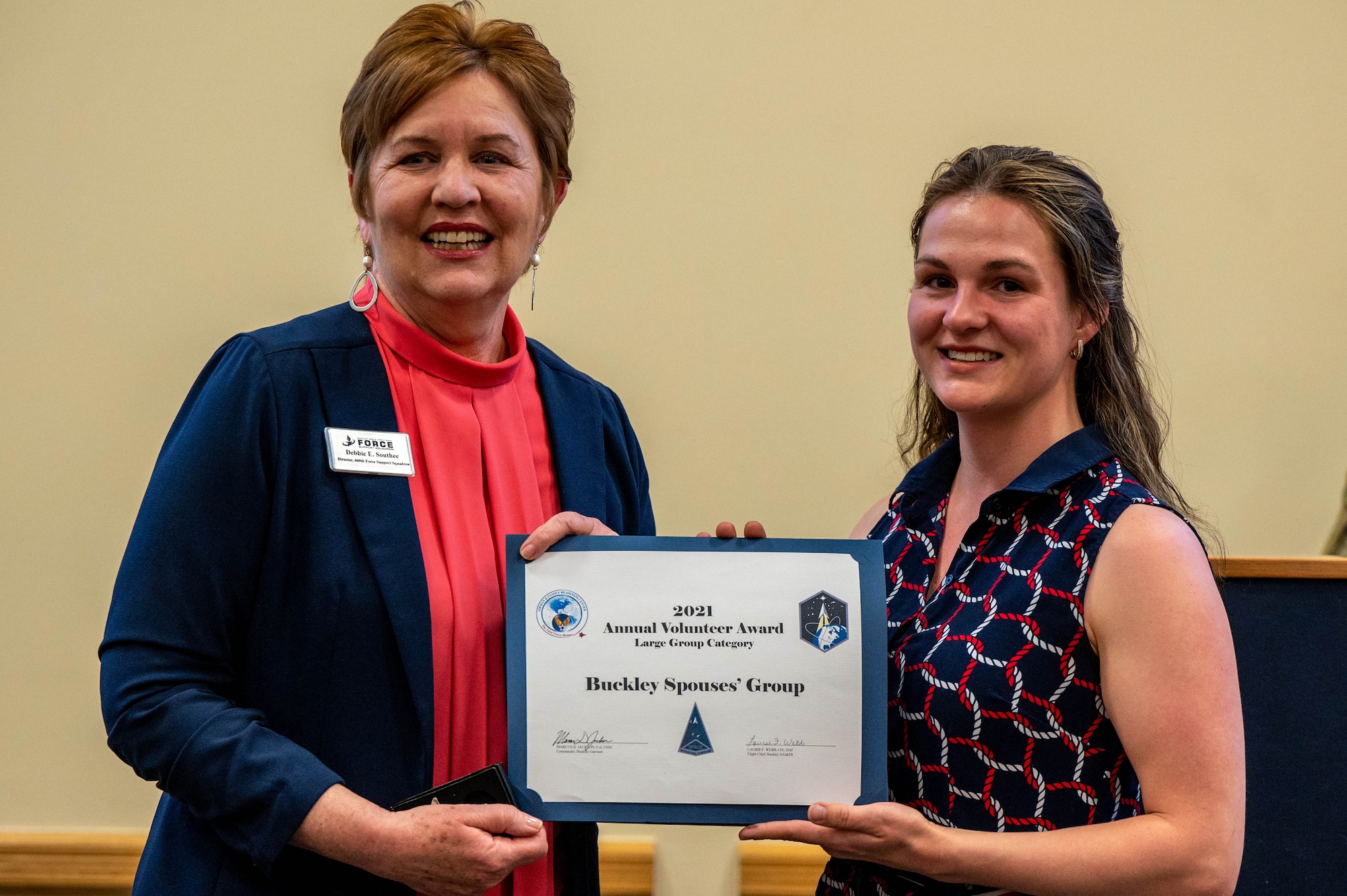 Scarlet Byrne, A member of the Buckley Spouses’ Group, accepts an award on the behalf of the Buckley Spouses’ Group for volunteer excellence from Mrs. Debbie South, Director of the 460th Force Support Squadron  at Buckley Space Force Base, Colo., April 22, 2022.
