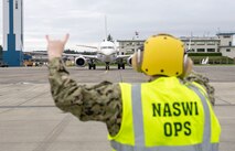 Aviation Boatswain�s Mate (Fuel) 3rd Class Killian Harriman, assigned to Naval Air Station (NAS) Whidbey Island Operations Air Terminal, guides a Boeing C-40 Clipper aircraft for departure on Ault Field.