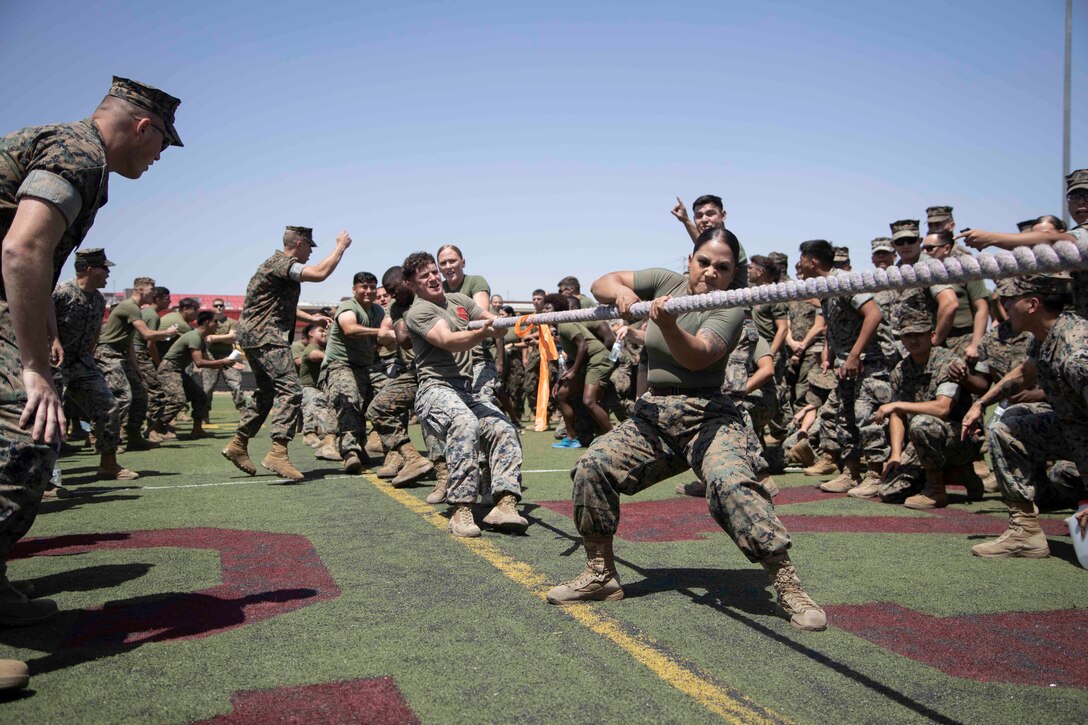 Marines grimace as they pull on a rope during a tug of war.