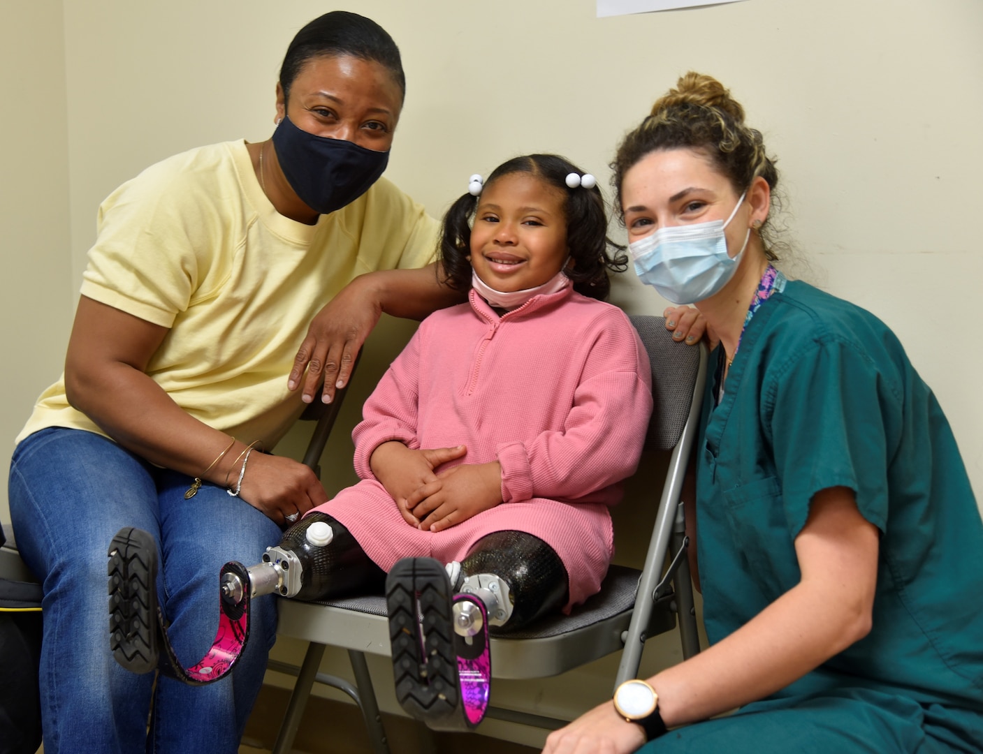Paisley Minor, center, poses for a photo with her mom United States Marine Corps. Maj. Paige Thomas, left, and Jaime Boehm, a prosthetist at Walter Reed National Military Medical Center (WRNMMC) in Bethesda, Maryland, April 20, 2022. Paisley and her mom come to WRNMMC often to receive prosthetics maintenance and support.