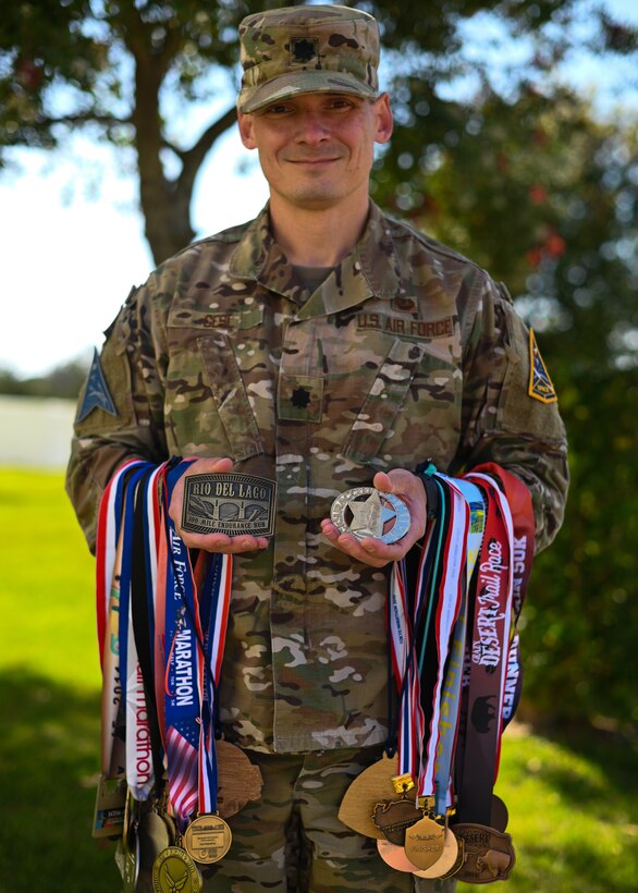 U.S. Air Force Lt. Col. Paul Gesl, Space Launch Delta 30 30th Staff Judge Advocate, poses with all his running medals that he has won over the last several years on Vandenberg Space Force Base, Calif., May 5, 2022. Gesl started running marathons in 2008 and has continued since. (U.S. Space Force photo by Airman 1st Class Kadielle Shaw)