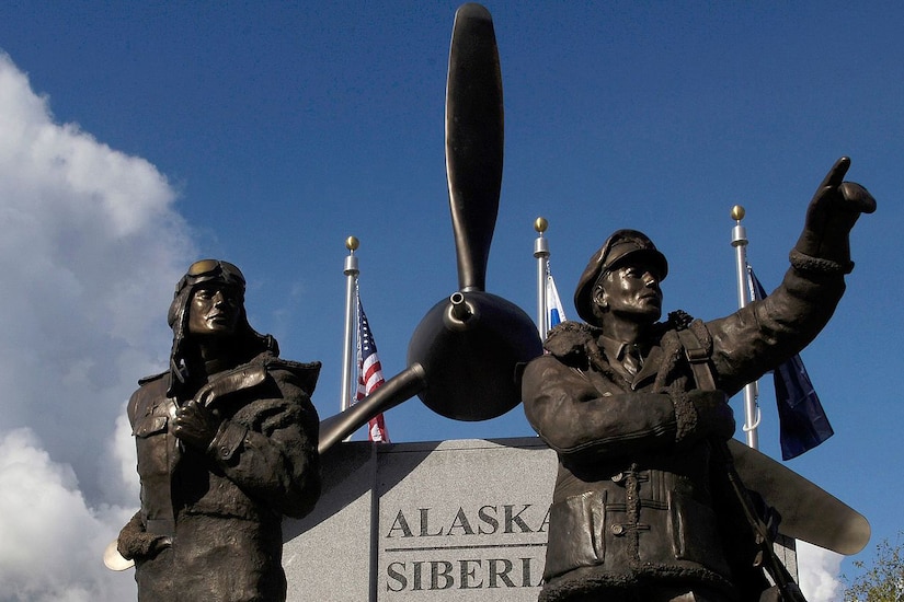 A statue of two men in front of an airplane propeller is shown.