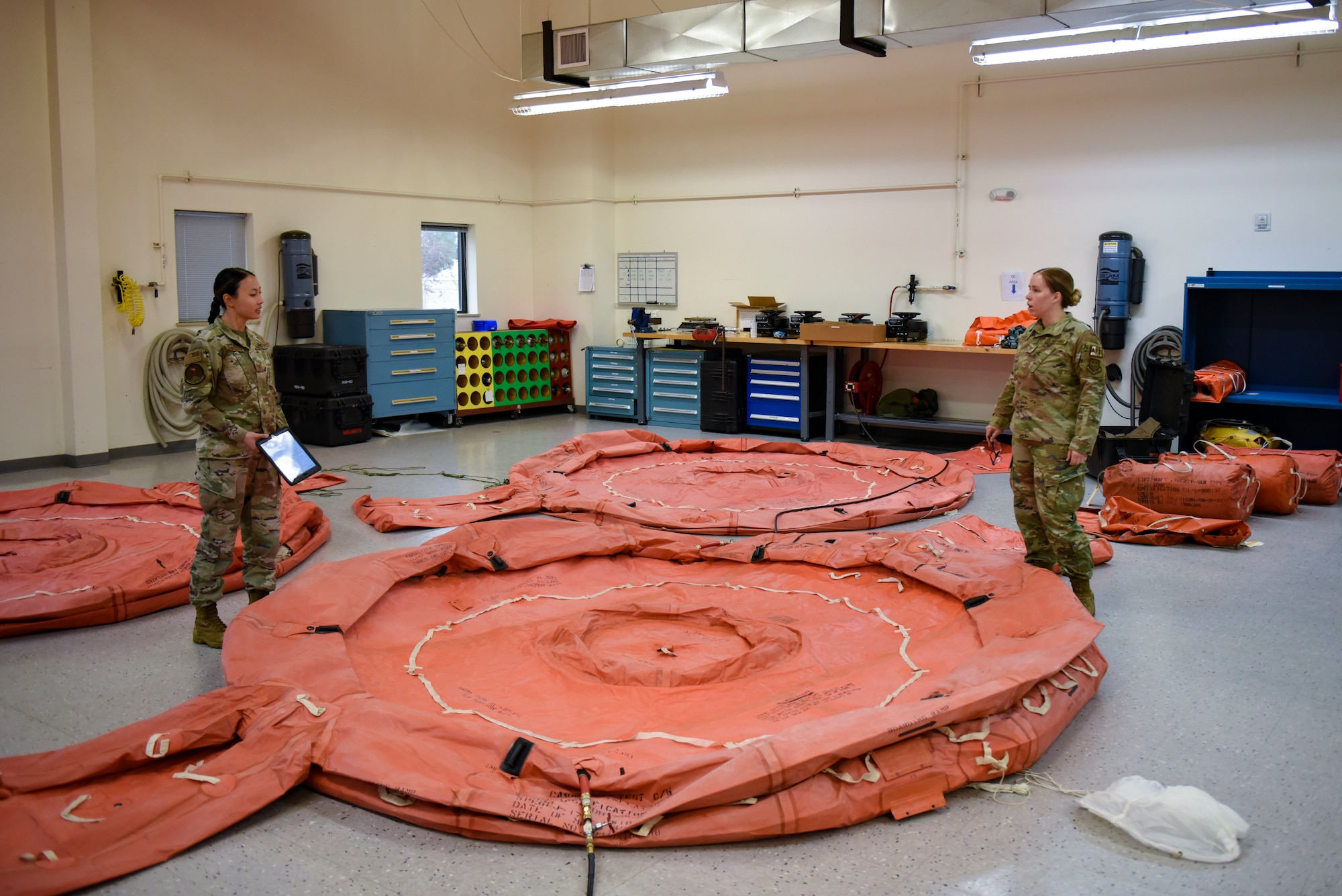 U.S. Air Force Staff Sgt. Lillie Schindlbeck, 92nd Operation Support Squadron Aircrew Flight Equipment technician, (left) goes over the procedure for inflating a 20 man raft with  Staff Sgt. Nicole Harper, 92nd OSS AFE technician, (right) on Fairchild Air Force Base, Washington, May 3, 2022. AFE ensures mission readiness and safety by thoroughly examining and repairing essential gear. (U.S. Air Force photo by Airmen 1st Class Haiden Morris)