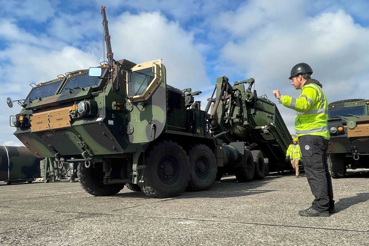 A man guides heavy military equipment.