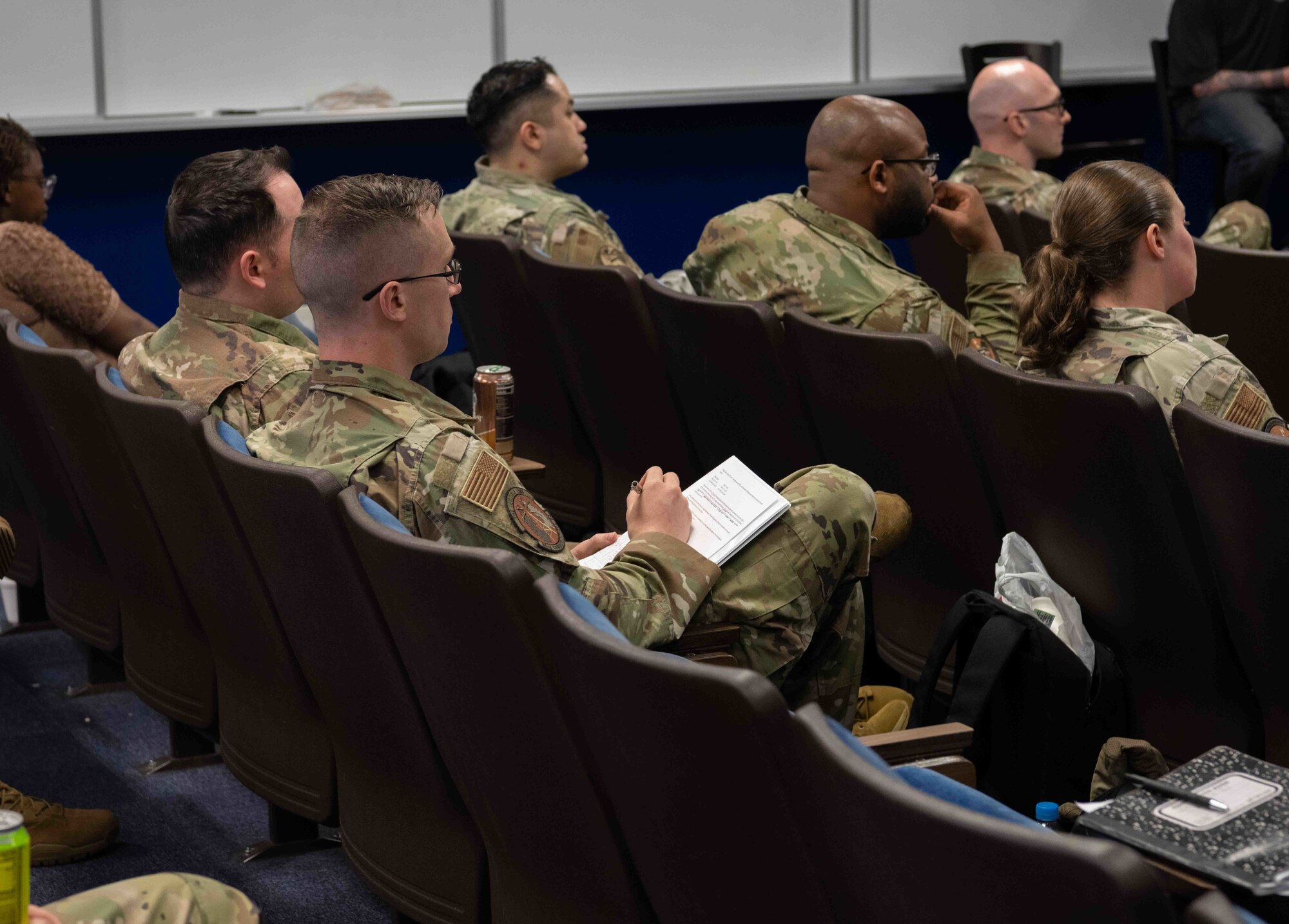 A military member writes on a notepad during an explanation.