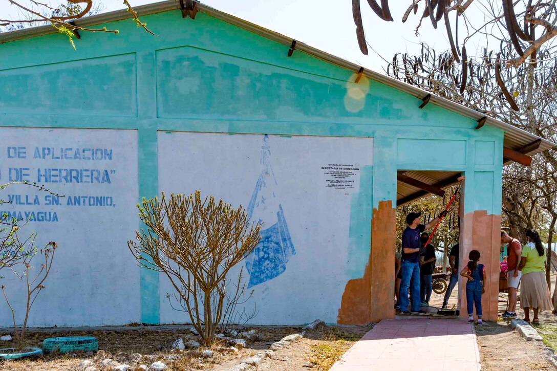 Service members paint a school.