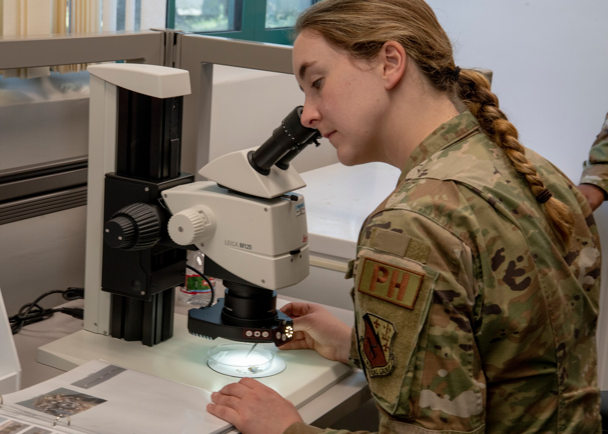 Senior Airman Hannah Jones-Trudeau, 104th Medical Group public health technician looks into a microscope at a specimen at Tripler Army Medical Center, Hawaii, May 3, 2022. Jones- Trudeau is at Tripler to provide medical support and complete training requirements.(U.S. Air National Guard Photo by 1Lt. Amelia Leonard).