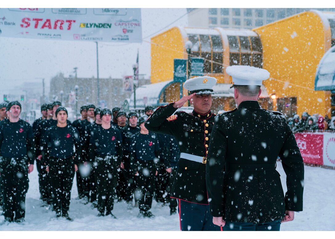 U.S. Marine Corps Sgt. Maj. Abelardo Dominguez, the sergeant major for Recruiting Station Portland, renders a salute to U.S. Marine Corps Maj. Matthew Krempel, the commanding officer for Recruiting Station Portland, during a swear-in ceremony at the 2022 Iditarod Trail Sled Dog Race in Anchorage, Alaska on March 5, 2022. The Marines had the opportunity to conduct a swear-in ceremony under the start banner and educate spectators about the opportunities the Marine Corps has to offer. The Iditarod is an annual race in Alaska that stretches over 900 miles, starting in Anchorage and ending in Nome. (U.S. Marines Corps photo by Sgt. Menelik Collins)