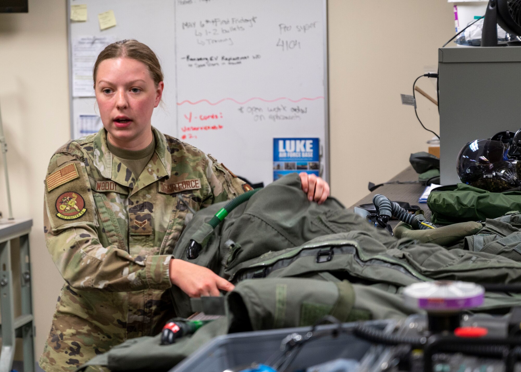 U.S. Air Force Airman 1st Class Hope Woody, 56th Operations Support Squadron aircrew flight equipment technician, explains to members from the Arizona Congressional Staff Delegation, how pilots use various pieces of equipment during a visit, May 4, 2022, Luke Air Force Base, Arizona.