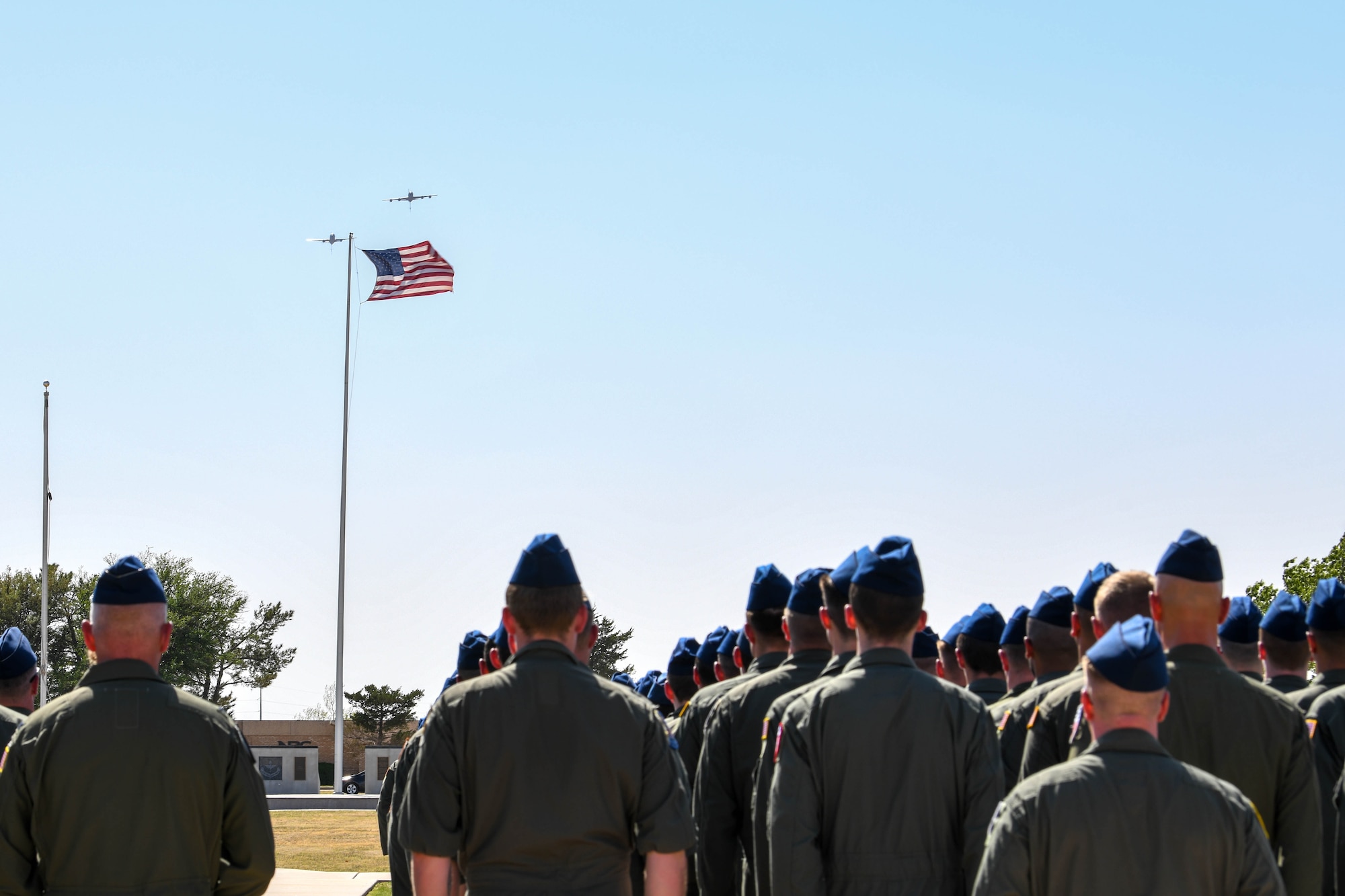Airmen stand at attention during a flyover at the 97th Air Mobility Wing’s 42nd Annual Boom Symposium at Altus Air Force Base, Oklahoma, April 29, 2022. The flyover included a KC-46 Pegasus and a KC-135 Stratotanker. (U.S. Air Force photo by Airman 1st Class Trenton Jancze)