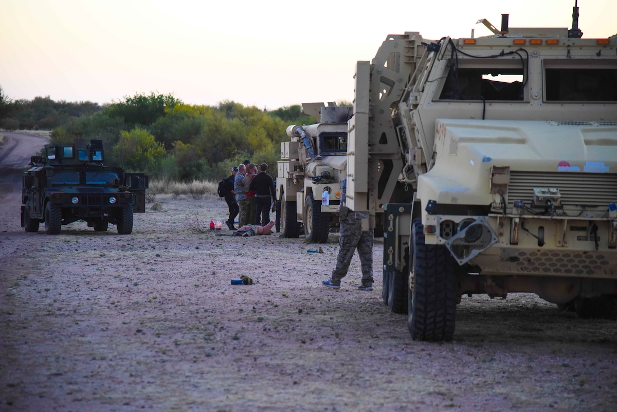 A phot of a line of trucks with mock patients standing by them.
