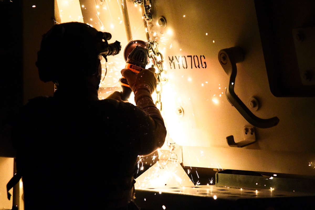 A photo of an Airman using a saw to cut a chain.