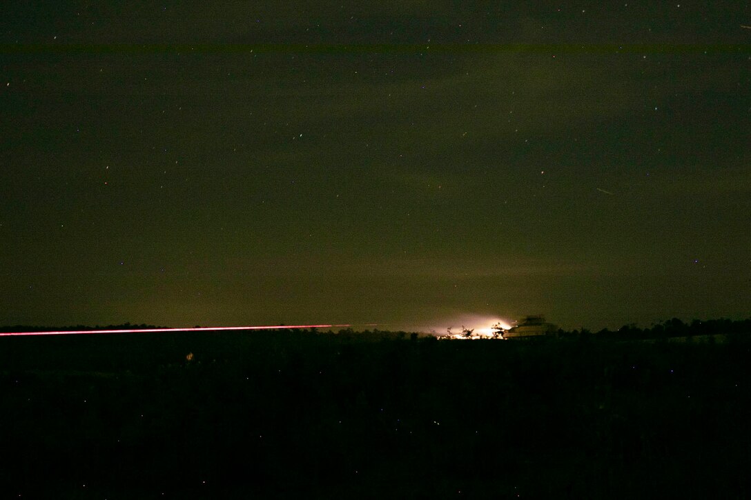 An Army tank fires at night.