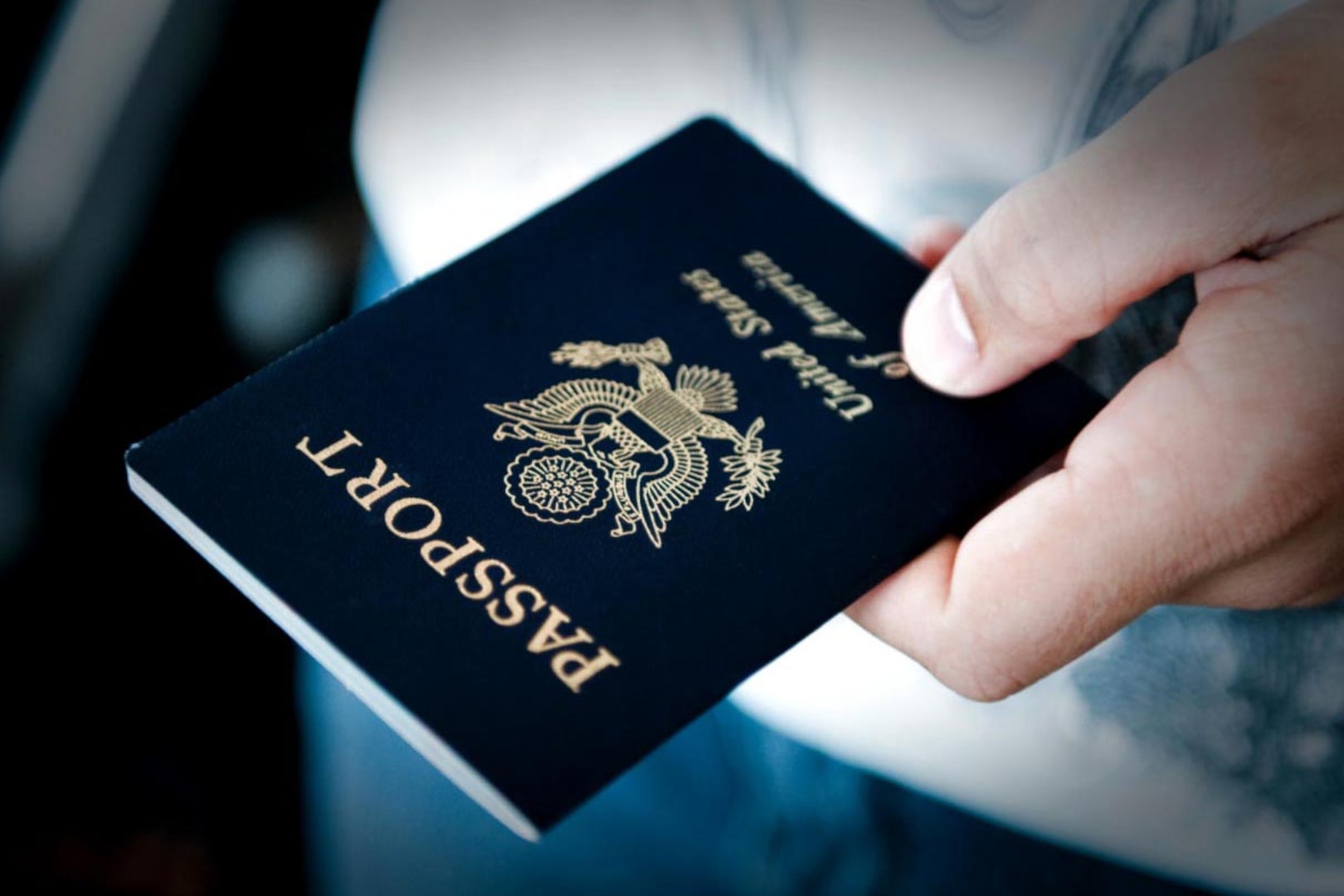 A blue passport book is held in a hand.