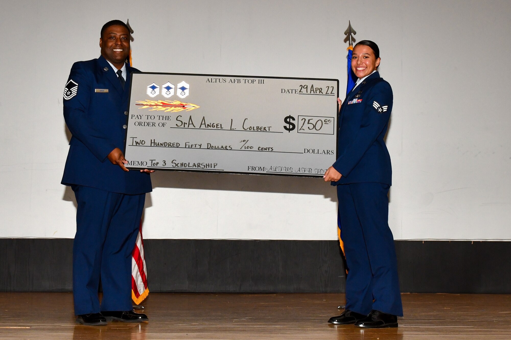 U.S. Air Force Master Sgt. Kelvin Lucky, 97th Security Forces Squadron superintendent of installation security, presents an Altus Top Three scholarship to Senior Airman Angel Colbert,97th Mission Support Group plans and operations lead, during a Community College of the Air Force graduation at Altus Air Force Base, Oklahoma, April 20, 2022. The Top Three  scholarship is given to outstanding performers seeking a higher education. (U.S. Air Force photo by Airman 1st Class Miyah Gray)