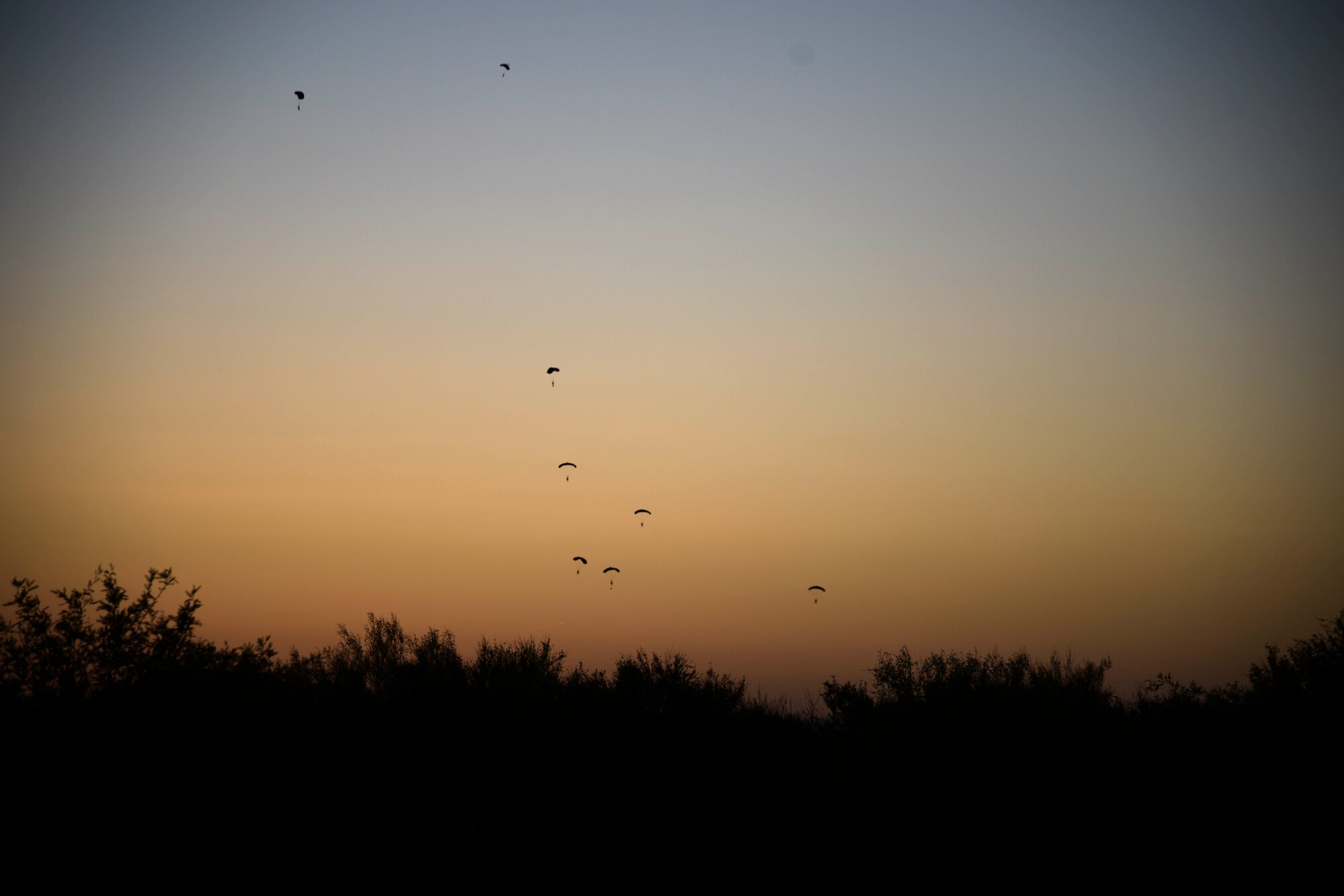 A photo of multiple Airmen parachuting to their designated drop zone.