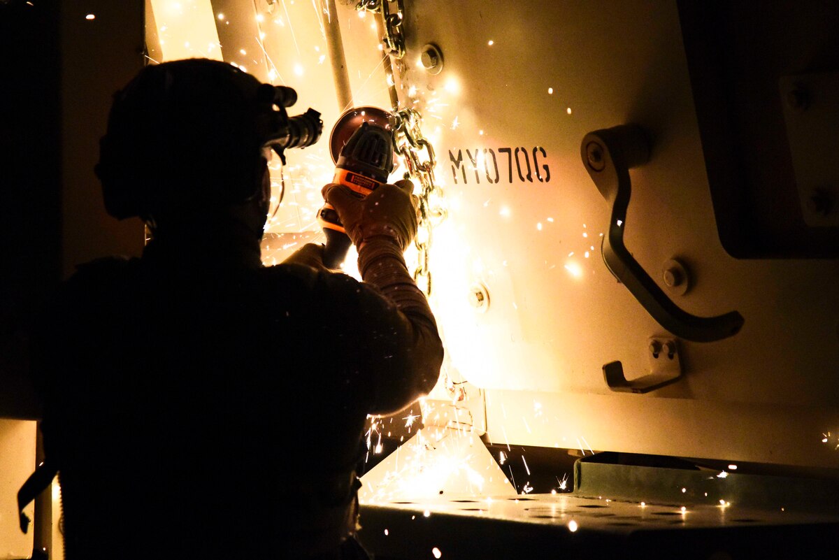 A photo of an Airman using a saw to cut a chain.