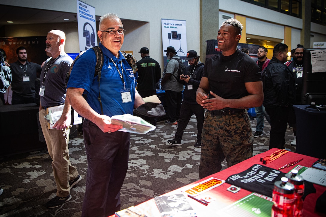 U.S. Marine Corps Sgt. Andre C. Henry, a recruiter with Recruiting Sub-Station Lakewood, Recruiting Station Orange County, speaks with Jamie Ramirez, a coach from Beaumont High School, during a Glazier Football Clinic in Costa Mesa, California, Feb. 26, 2022. The Glazier Clinic is a coaching program constructed for high school coaches who are dedicated to improving their craft and bettering their athletes. (U.S. Marine Corps photo by Cpl. Emely Gonzalez)