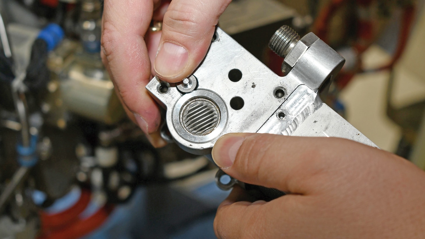 A close view of a clutch servo-valve filter on an auxiliary power unit for a V-22 Osprey. This quarter-sized filter is part of a critical oil line that helps engage the APU clutch to the midwing gearbox in order to start the V-22’s main engines.