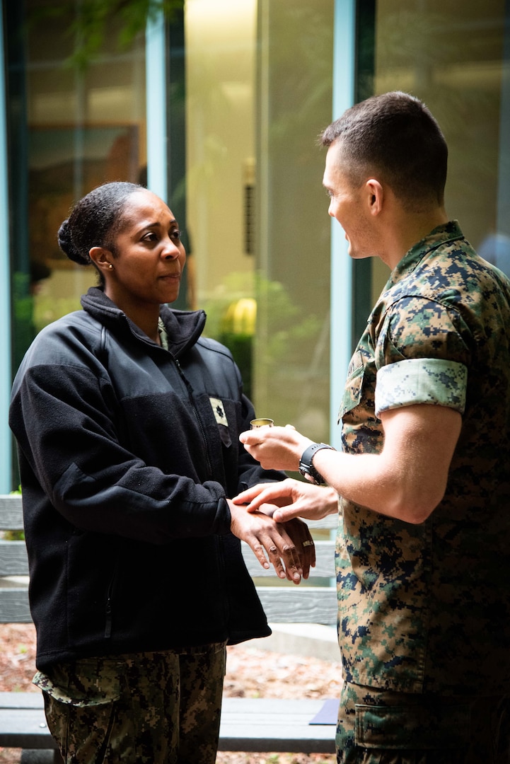 Navy Lieutenant Junior Grade Chaplain Kyle Lambertson, right, anoints the hands of Chief Petty Officer Raymond Weeks during a Blessing of the Hands ceremony held Wednesday, May 11.  The ceremony included prayer and anointing of a caregiver’s hands with oil.