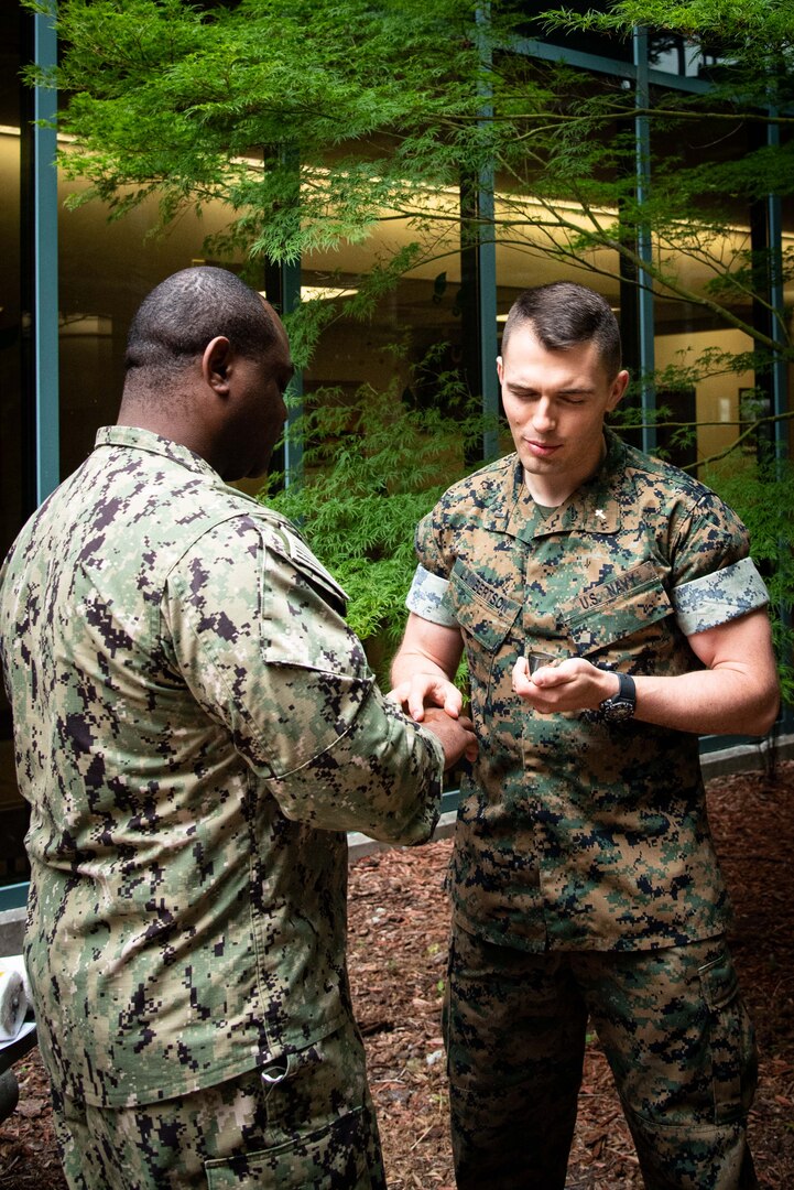 Navy Lieutenant Junior Grade Chaplain Kyle Lambertson, right, anoints the hands of Chief Petty Officer Raymond Weeks during a Blessing of the Hands ceremony held Wednesday, May 11.  The ceremony included prayer and anointing of a caregiver’s hands with oil.