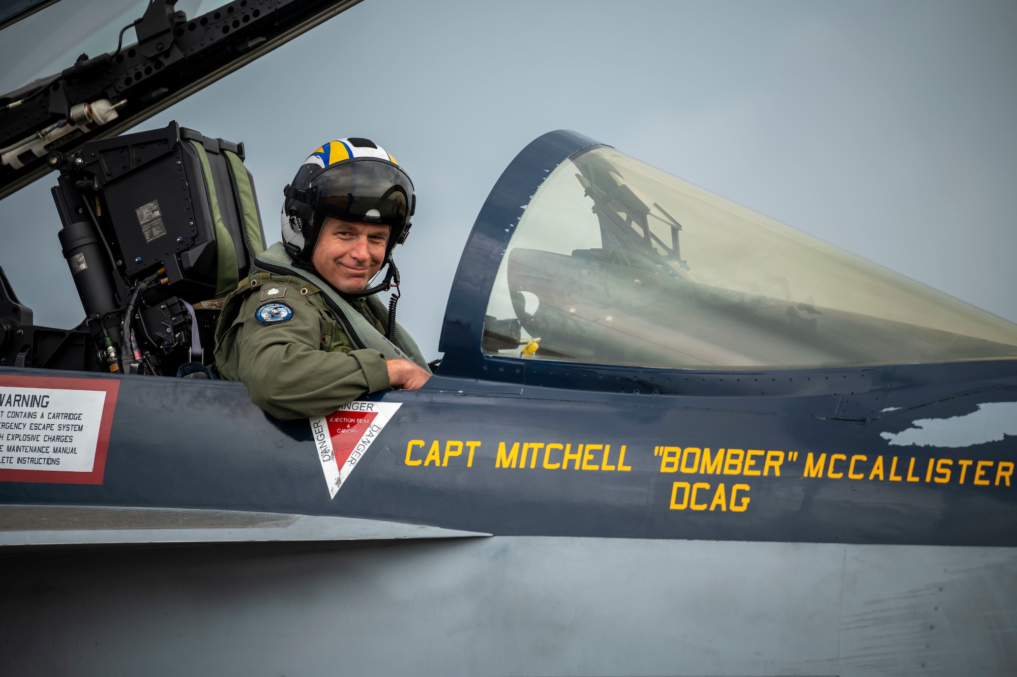 A pilot sitting in the cockpit of an aircraft poses for a photo