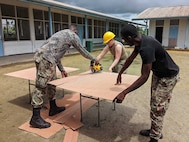 A South Dakota Army National Guard engineer works
alongside Suriname Defense Force soldiers as they conduct renovations at the Magenta Polder (Elementary) School in Suriname, April 22, 2022, as a part of the Suriname and South Dakota State Partnership Program agreement. About 30 soldiers from the South Dakota National Guard traveled to the South American country of Suriname to provide engineering support for a school renovation and medical and dental services in several community locations.