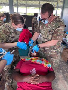 South Dakota Air National Guard airmen perform a
dental examination of a Surinamese woman in Suriname, April 22, 2022, as a part of the Suriname and South Dakota State Partnership Program agreement. About 30 soldiers from the South Dakota National Guard traveled to the South American country of Suriname to provide engineering support for a school renovation and medical and dental services in several community locations.