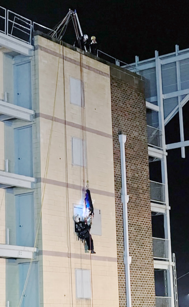 Man hangs by a rope outside a buidling