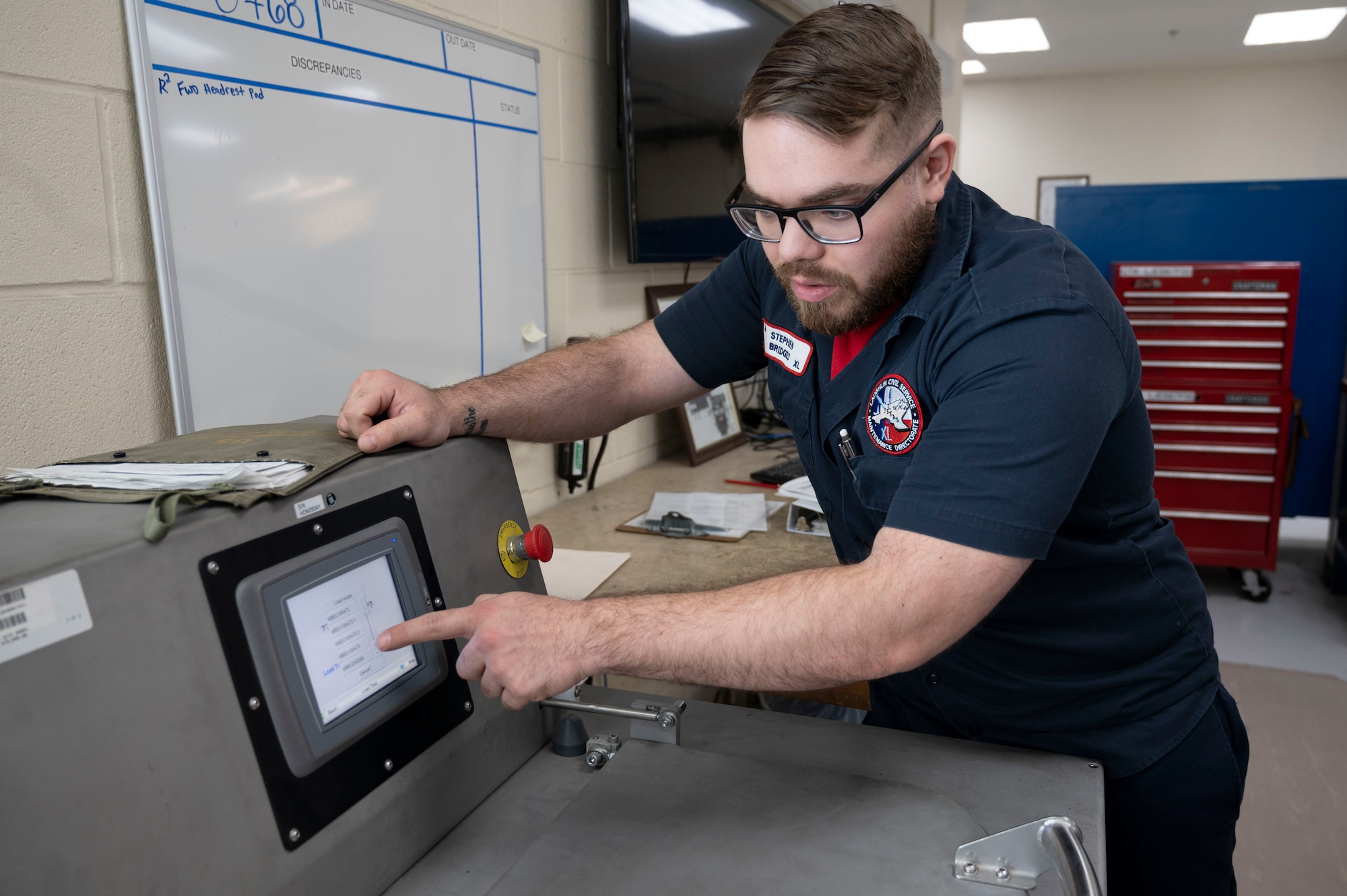 Stephen Bridges, 47th Maintenance Directorate aircraft ordnance technician, shows the camera the operation options of a machine he uses to make sure that each ejection seat is successful in its performance at the Egress Shop on Laughlin Air Force Base, Texas, April 8, 2022. Bridges and his coworkers take apart, inspect, test, replace or repair the ejection seats that are in each aircraft at Laughlin daily to keep our pilots safe. (U.S. Air Force photo by Airman First Class Kailee Reynolds)