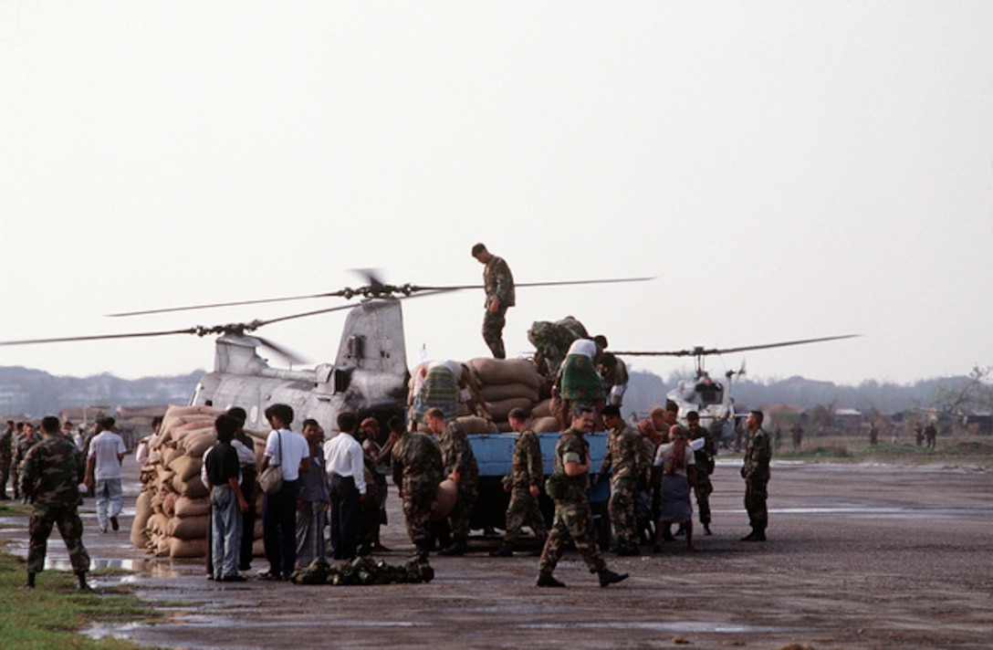 Local residents stand by as Marines load supplies onto a Marine Utility/Attack Helicopter Squadron 169 (HML/A-169) CH-46 Sea Knight helicopter at Chittagong Air Base during Operation Sea Angel, a U.S. military effort to provide disaster relief to victims of a cyclone which devastated Bangladesh on April 30th.