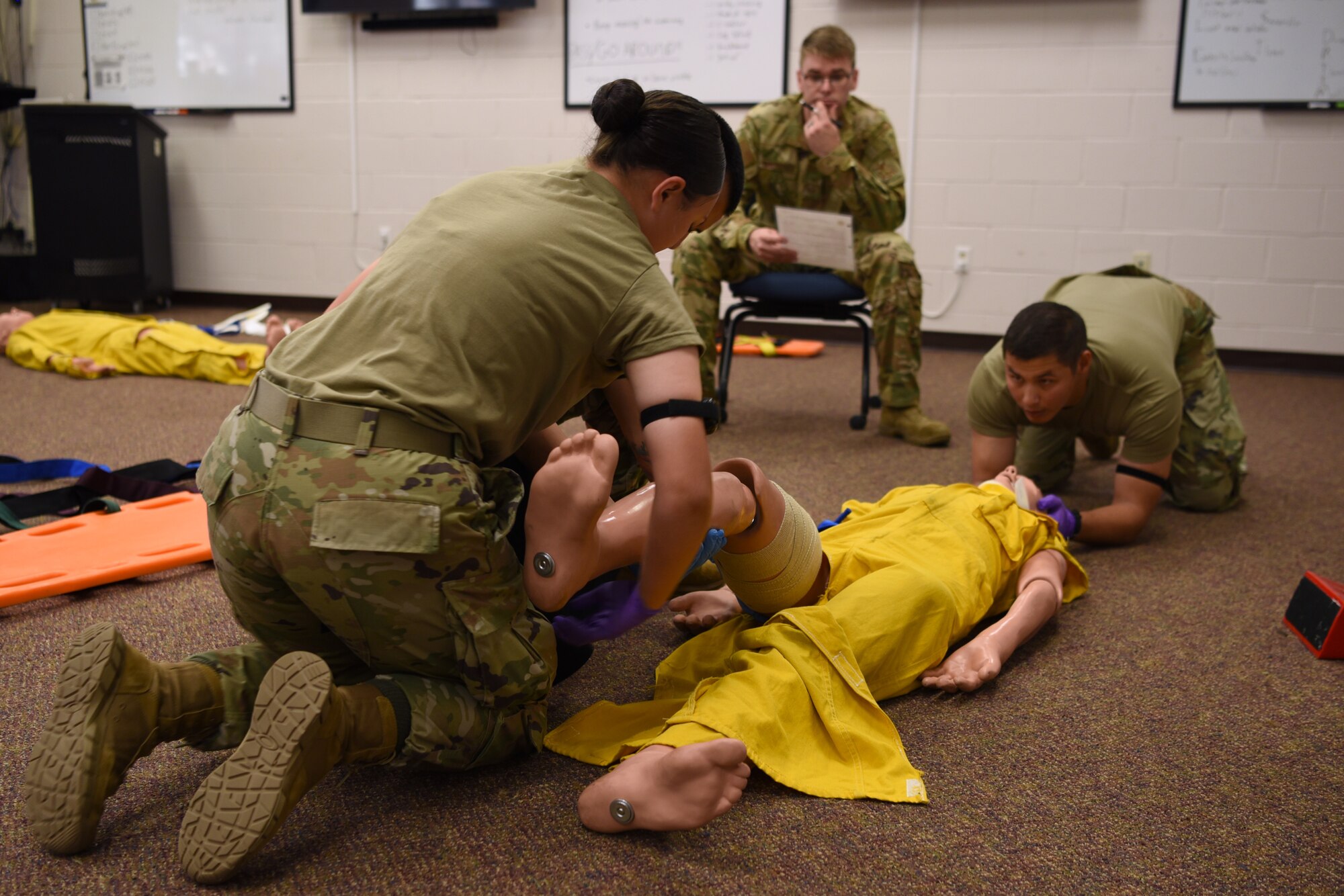 Joint service students assigned to the 312th Training Squadron, control the bleeding of a simulated open wound on an artificial victim’s lower extremity, during an Emergency Medical Responder psychomotor skills evaluation at Goodfellow Air Force Base, Texas, May 6, 2022. After securing the tourniquet, the students tightened it until they could not feel a distal pulse, which stops the bleeding in a real life situation. (U.S. Air Force photo by Senior Airman Abbey Rieves)