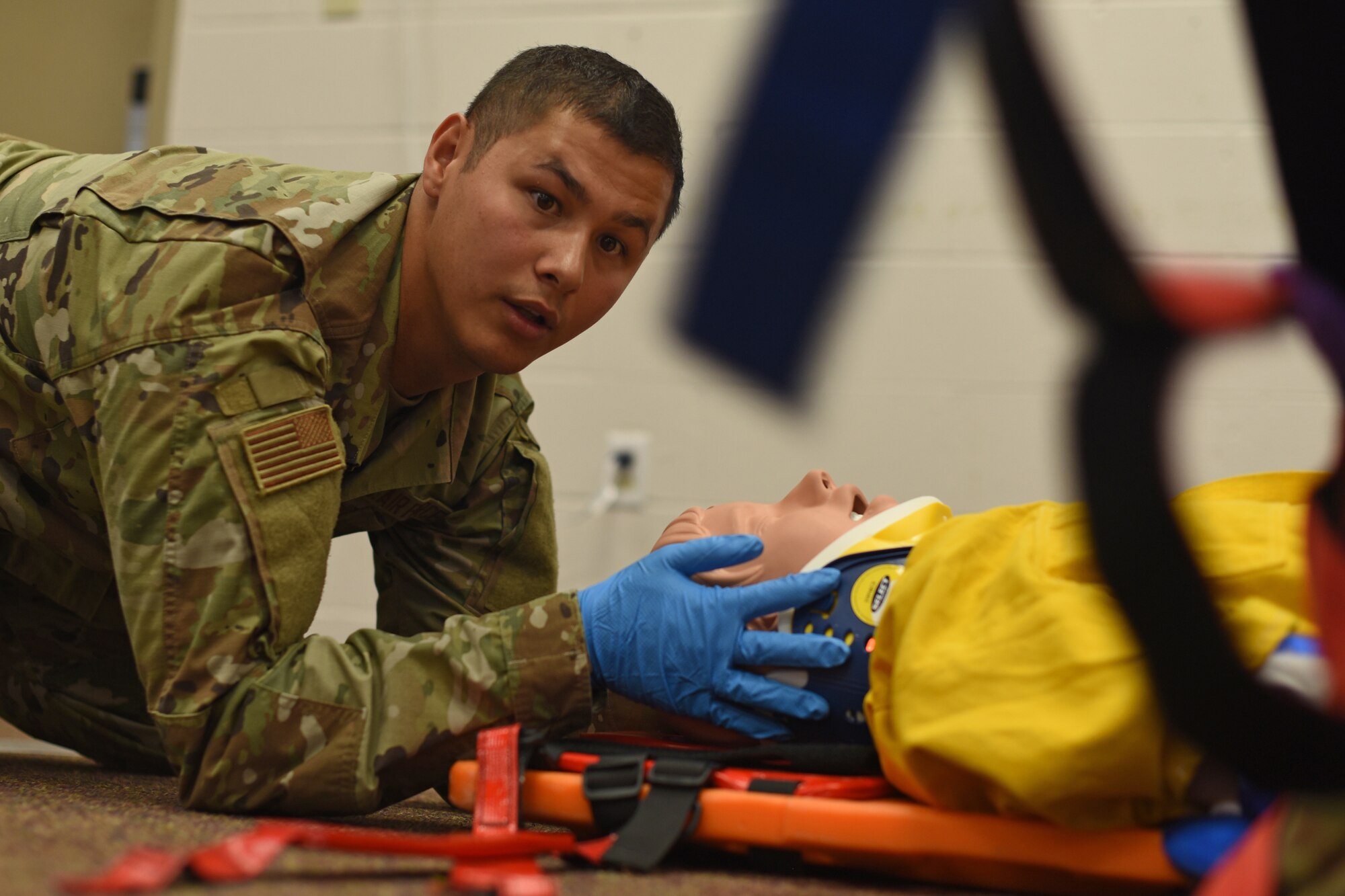 U.S. Air Force Airman Alec Almendarez, 312th Training Squadron student, verbalizes to his simulated victim that his partner is preparing straps to secure the simulated victim to a longboard for transportation to a hospital, during an Emergency Medical Responder psychomotor skills evaluation at Goodfellow Air Force Base, Texas, May 6, 2022. EMR psychomotor skills evaluation had 27 evaluation areas with patient communication considered a critical area in the assessment. (U.S. Air Force photo by Senior Airman Abbey Rieves)