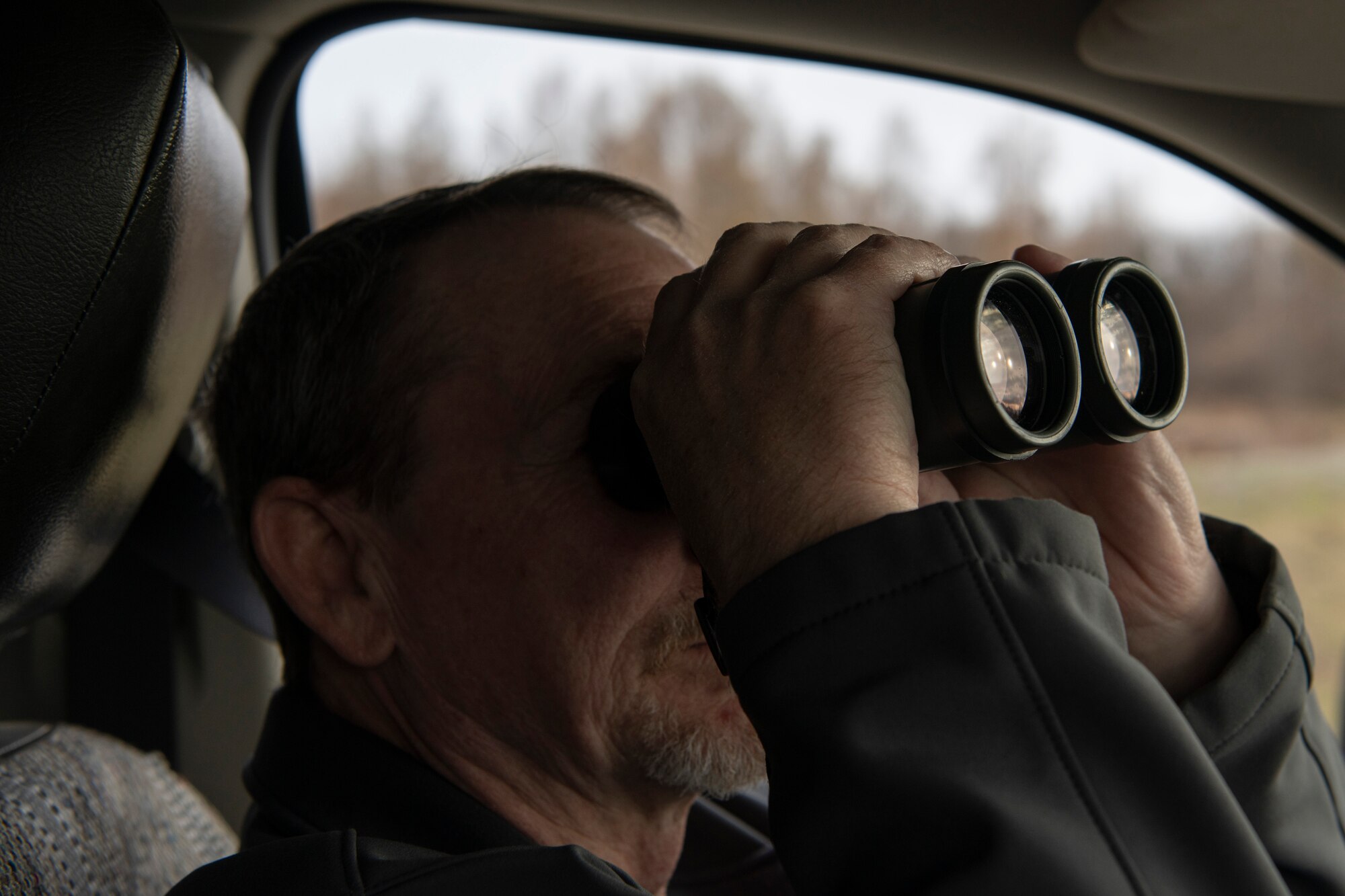 A photo of a man looking through binoculars