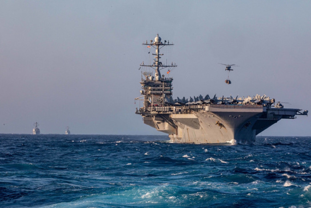 A helicopter hovers over a ship at sea.