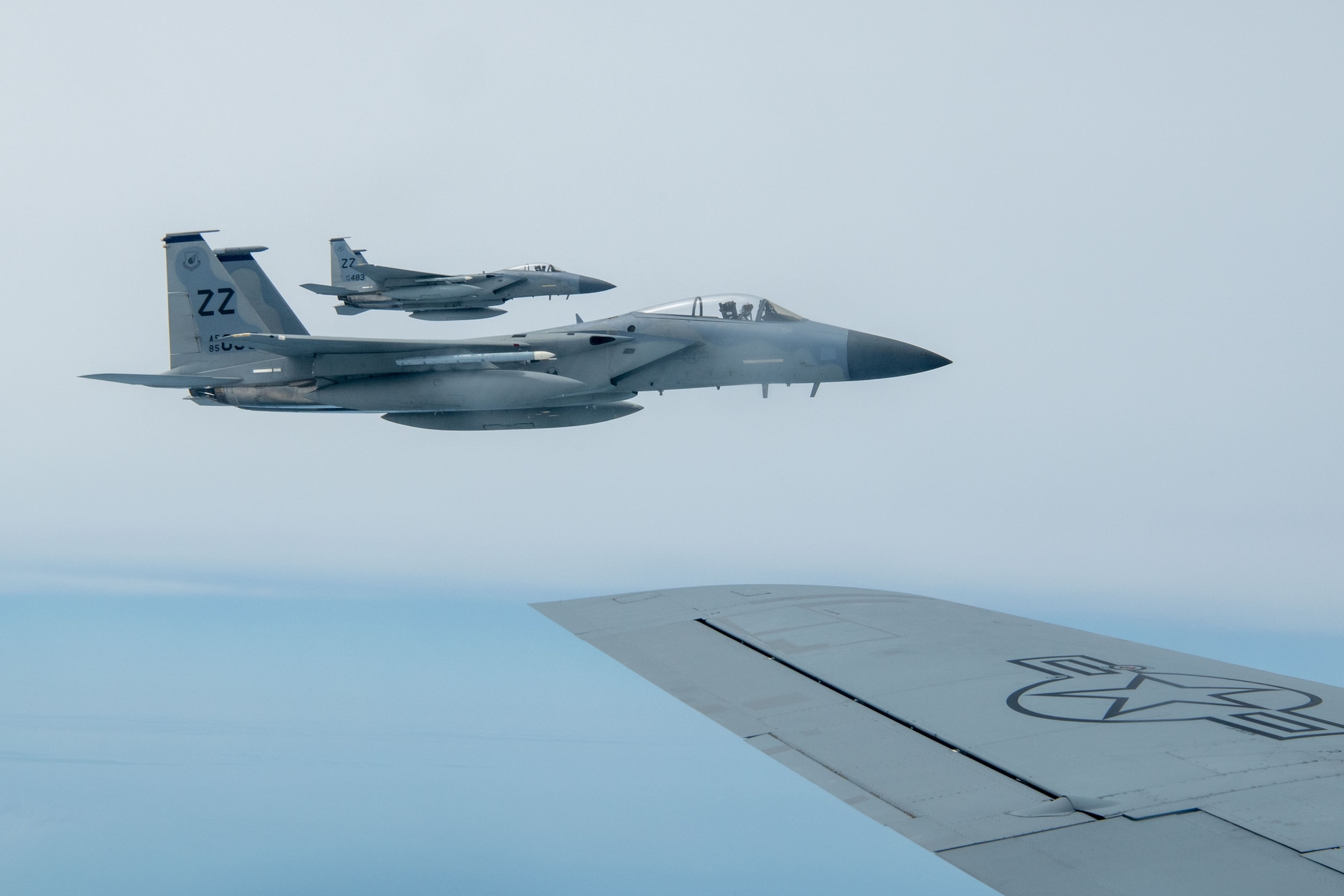 Two F-15 Eagles fly across the Pacific Ocean.